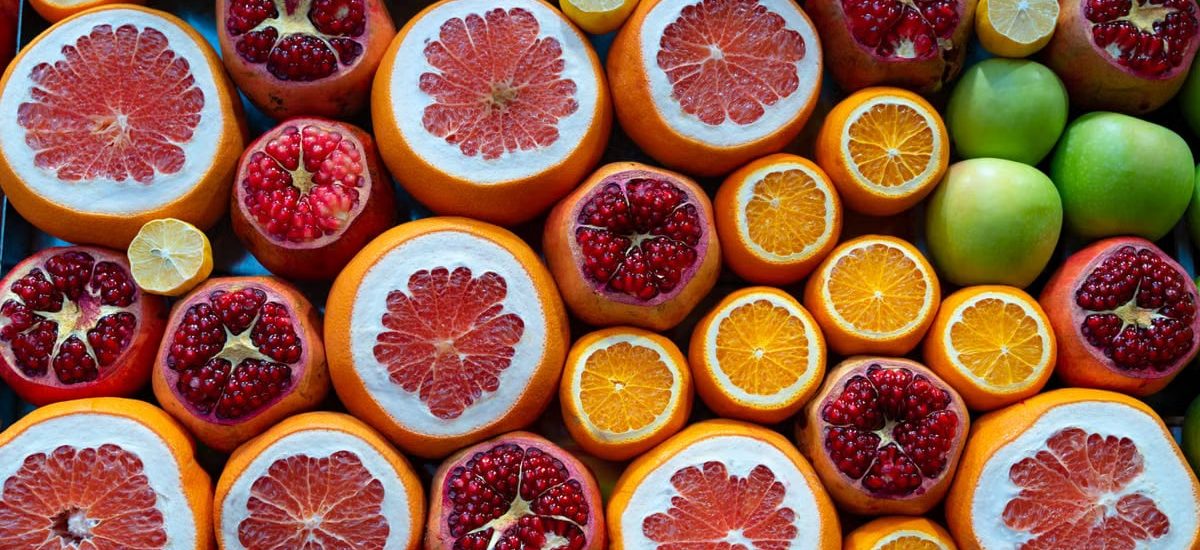 A colorful arrangement of sliced citrus fruits and pomegranates in a street market setting.