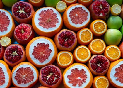 A colorful arrangement of sliced citrus fruits and pomegranates in a street market setting.